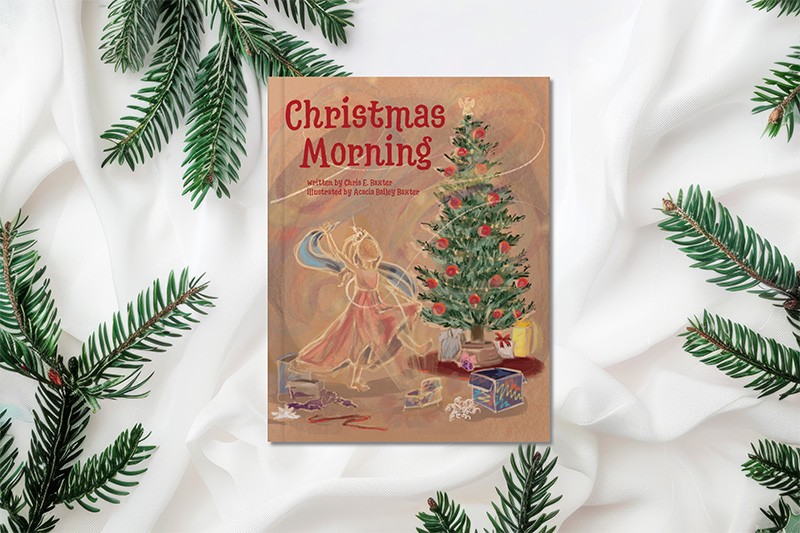 The book "Christmas Morning" by Chris E. Baxter on white fabric with fir branches