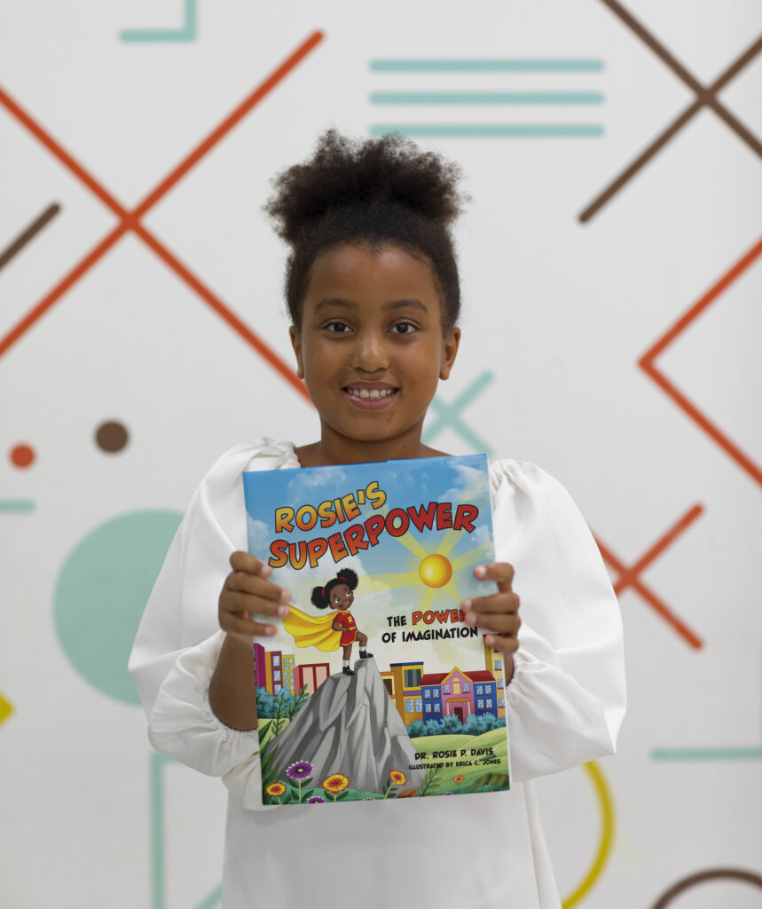 girl holding a copy of "Rosie's Superpower" by Rosie Phillips Davis (Author), Erica C. Jones (Illustrator) 